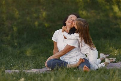 A joyful moment between mother and daughter hugging on a grassy field.